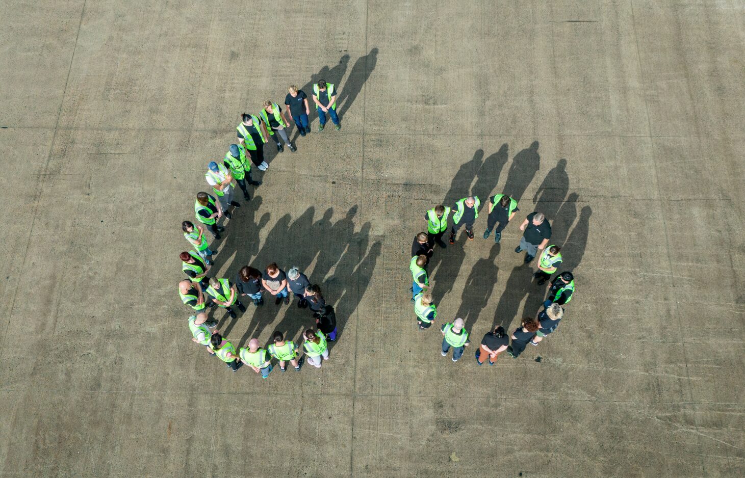 Staff members of ACS standing outside, making the shape of the number 60