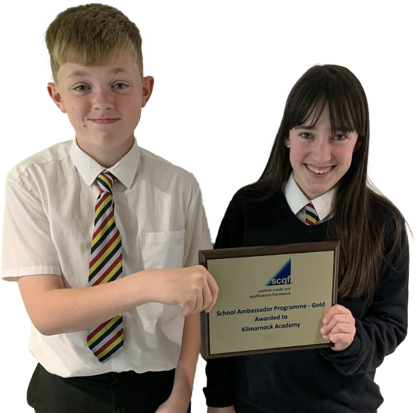 Two smiling school pupils from Kilmarnock Academy hold up a gold SCQF School Ambassador plaque. The school features on the SCQF School Ambassador Wall