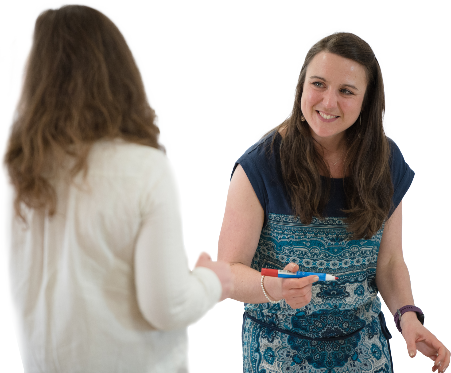 A woman stands white a white board pen in her hand, smiling and talking to a woman who is standing in front of her. They're taking part in an Award in Leadership qualification that is on the SCQF