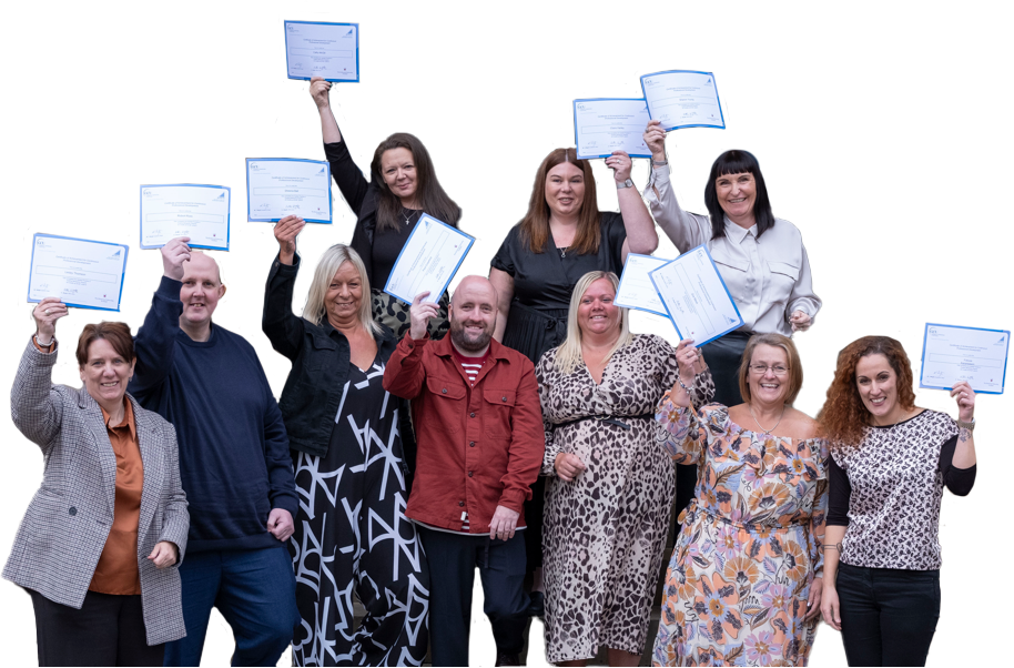 A group of adult learners who undertook a qualification that features on the SCQF while in the workplace. They are smiling, and holding up their certificates.