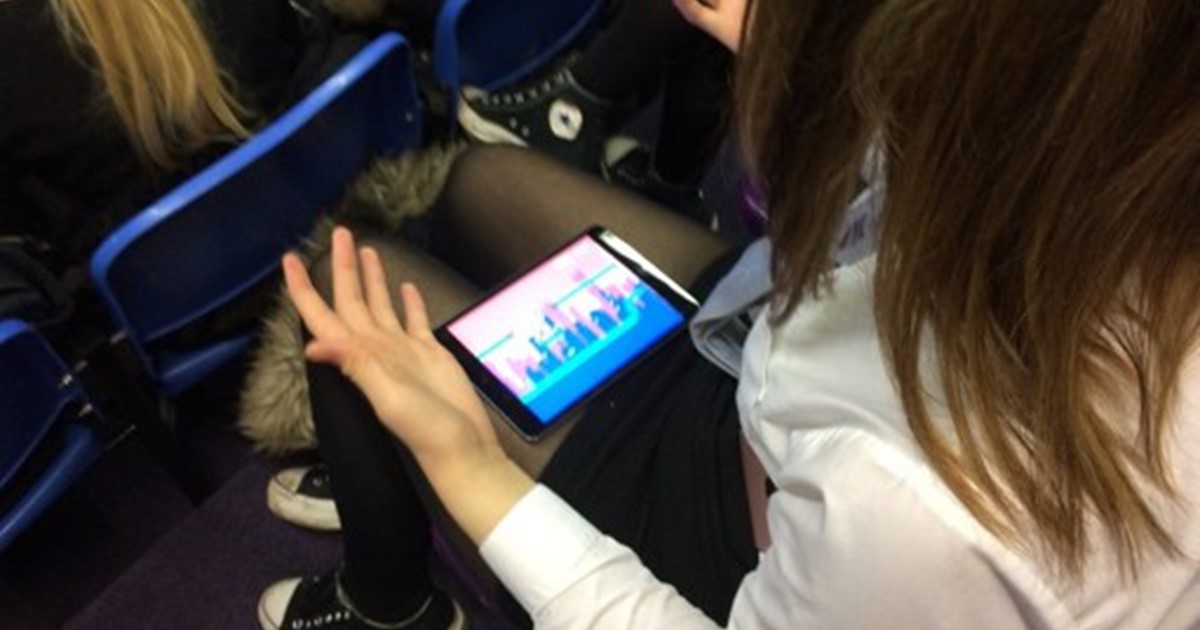 Schoolgirl looking at mobile phone on her knee