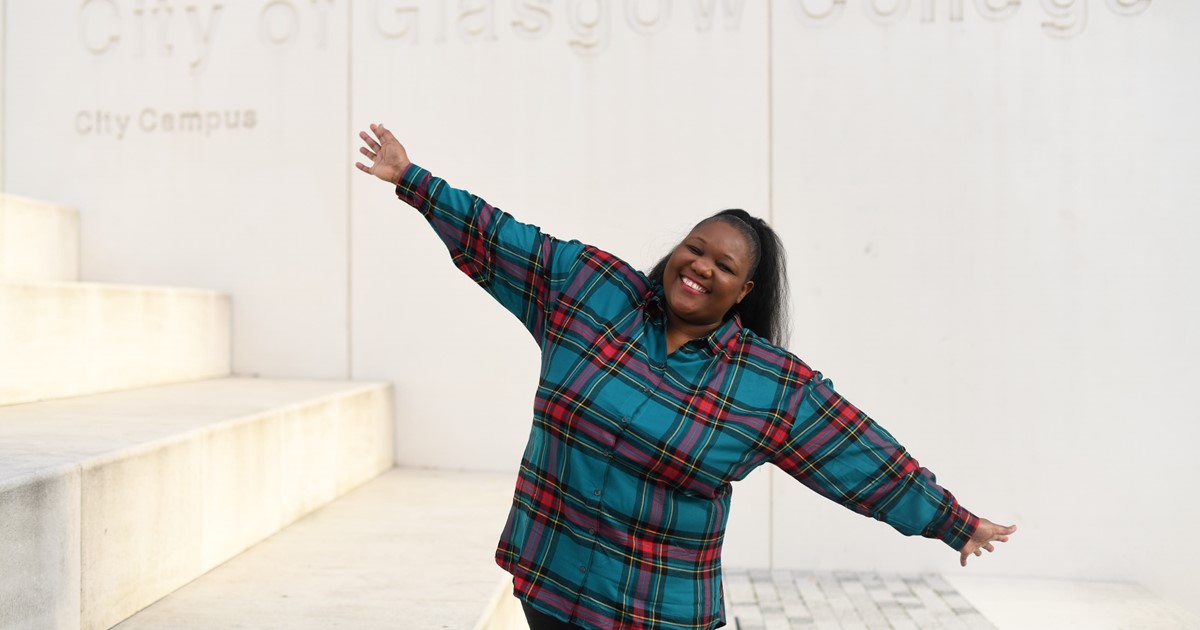 College student smiling and standing in front of entrance to City of Glasgow College
