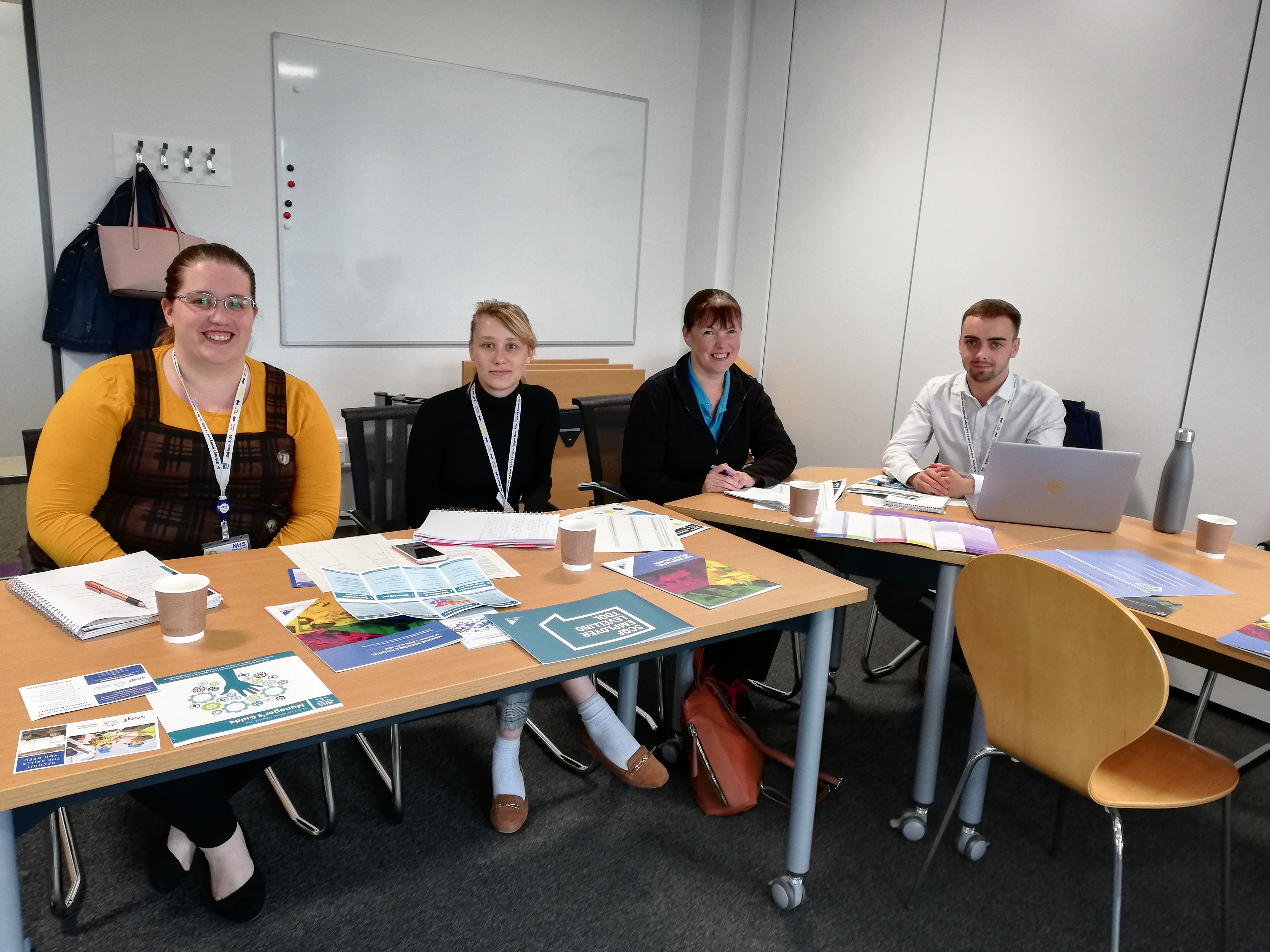 Group of male & female NHS Orkney staff sitting at desks in training room
