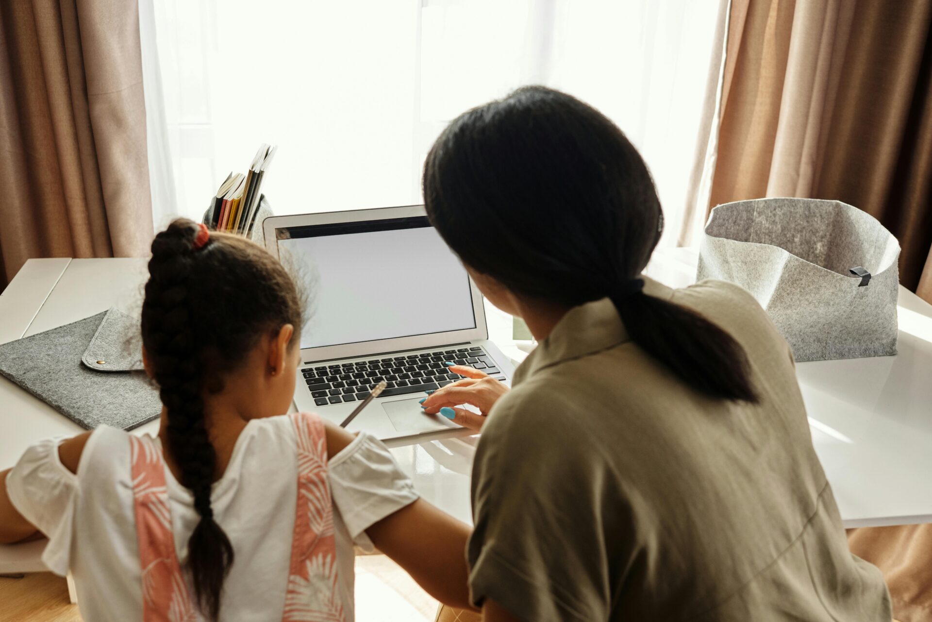 A parent and her daughter doing homework together on a laptop
