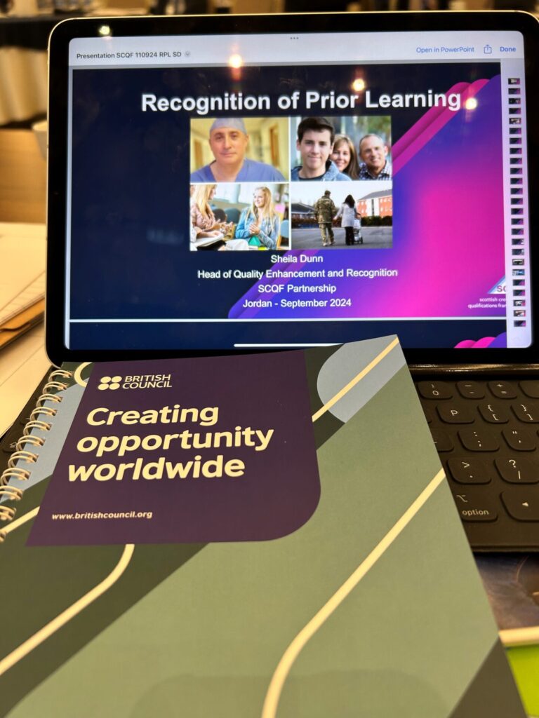 A laptop screen featuring a presentation titled 'Recognition of Prior Learning, by Sheila Dunn', alongside a booklet titled 'Creating opportunity worldwide'