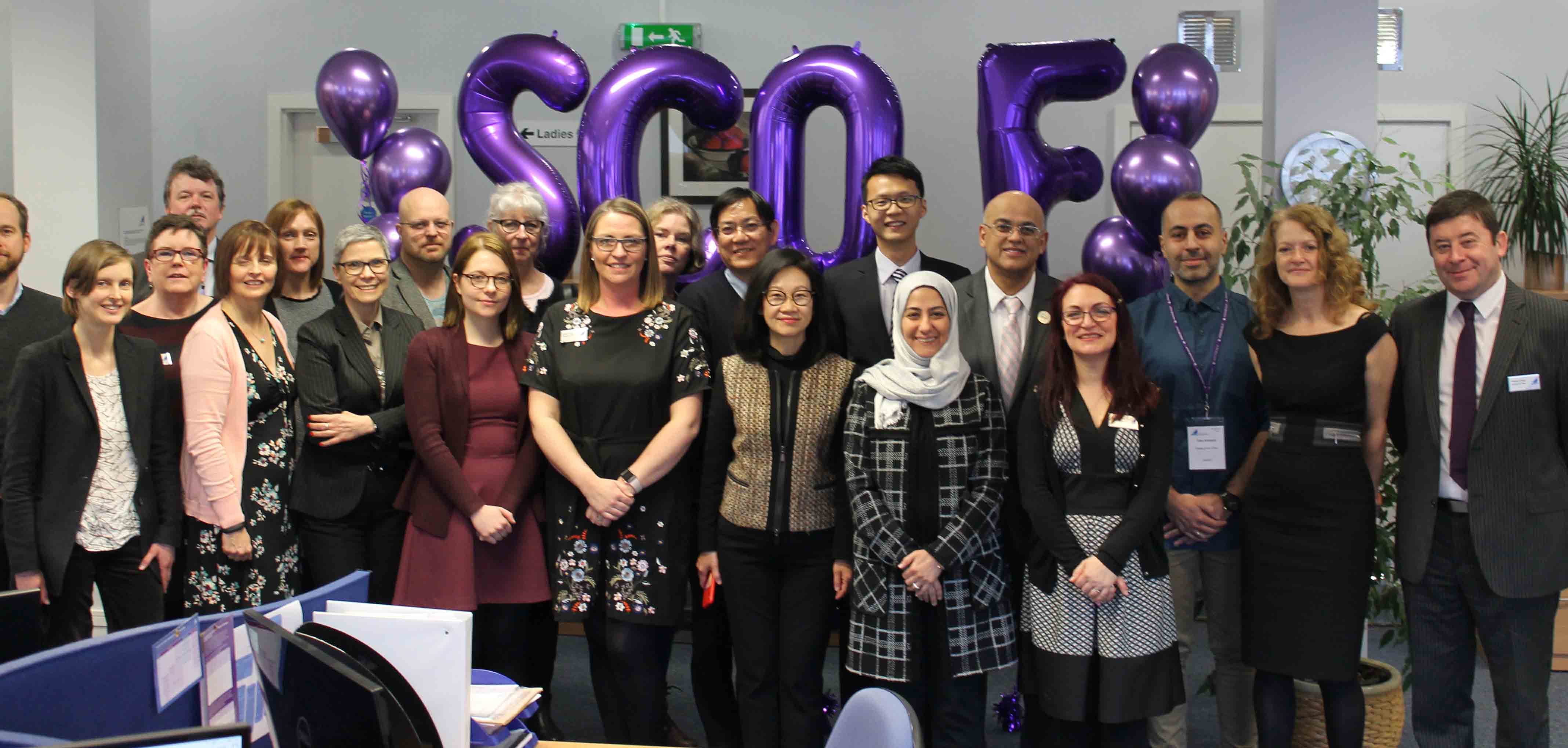 Group shot of SCQFP staff and delegates at international study visit event with purple balloons spelling out SCQF