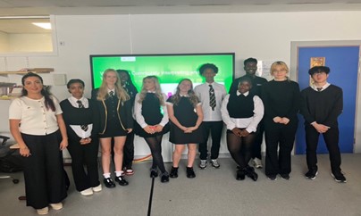 A group of students and their teacher at St Mungo’s Academy in the Gallowgate stand together in a classroom. They are participating in the Community Interpreting course at SCQF Level 5, which helps young people gain qualifications from their experience translating and interpreting English for their families