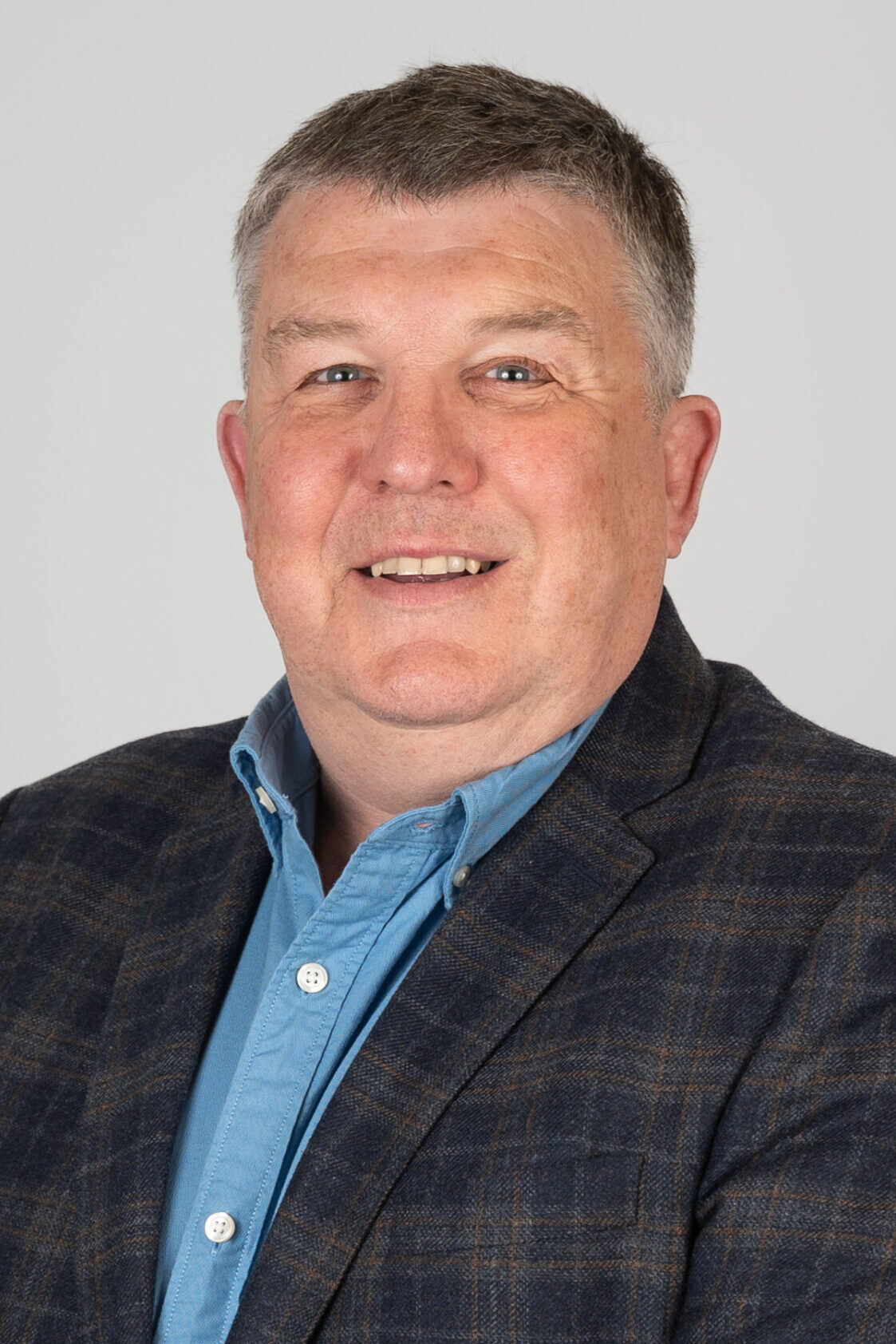 headshot of John Evans, in a blazer and shirt, smiling